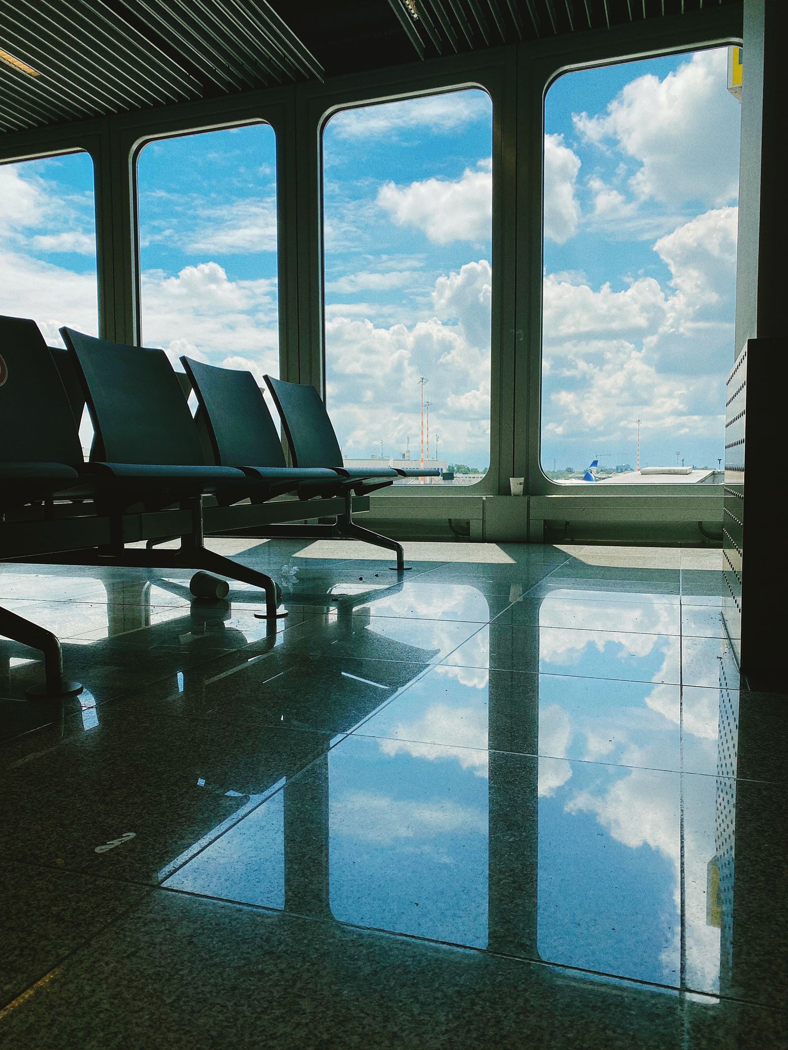 Calm airport lounge with large windows reflecting the sky