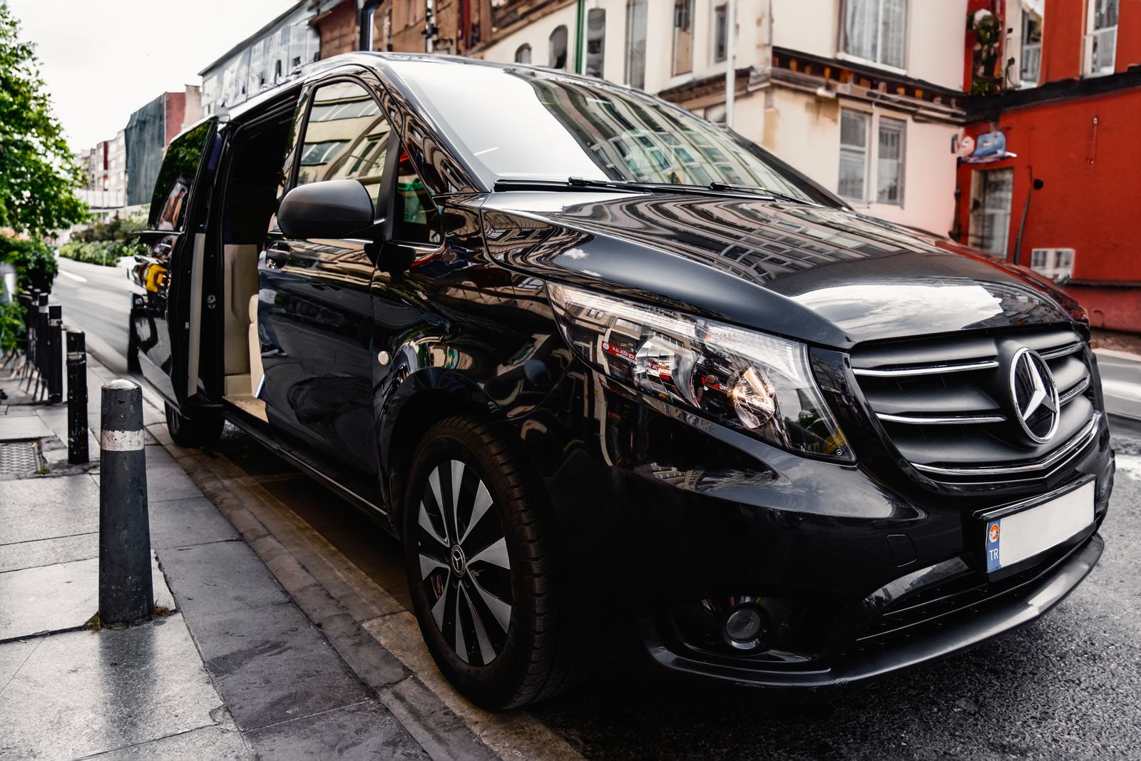 Black Mercedes-Benz V-Class parked at a city kerb with the side door open